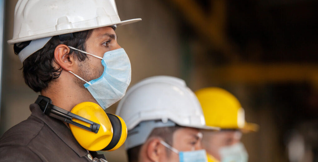 Workers wear protective face masks for safety in machine industrial factory. - The Risk Factor